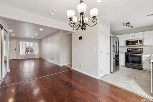 kitchen with open floor plan, stainless steel appliances, light countertops, and white cabinets