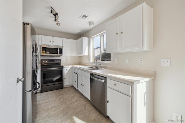 kitchen featuring stainless steel appliances, light countertops, a sink, and white cabinetry