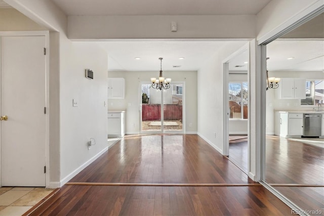 foyer featuring hardwood / wood-style floors, baseboards, and a notable chandelier