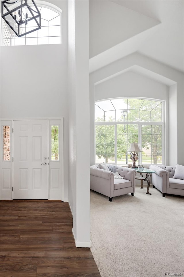 entrance foyer featuring a towering ceiling, plenty of natural light, dark hardwood / wood-style flooring, and a chandelier