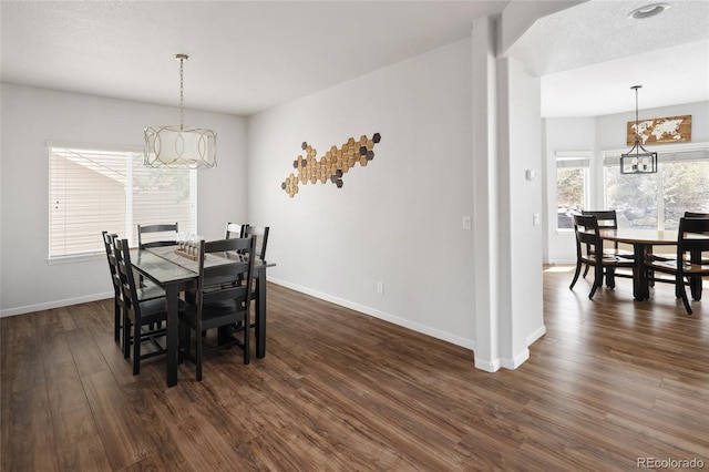 dining space with an inviting chandelier, dark hardwood / wood-style floors, and a textured ceiling