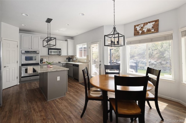 kitchen with appliances with stainless steel finishes, a center island, pendant lighting, and sink