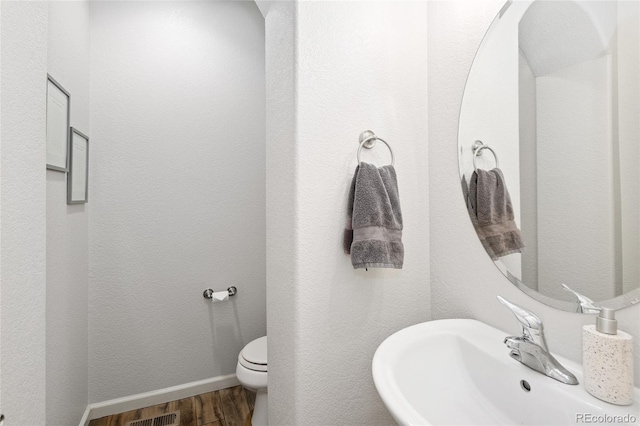 bathroom with wood-type flooring, toilet, and sink