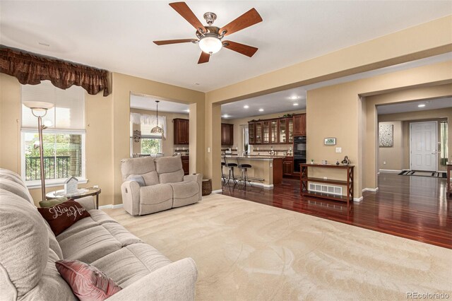 living room featuring ceiling fan and dark hardwood / wood-style flooring