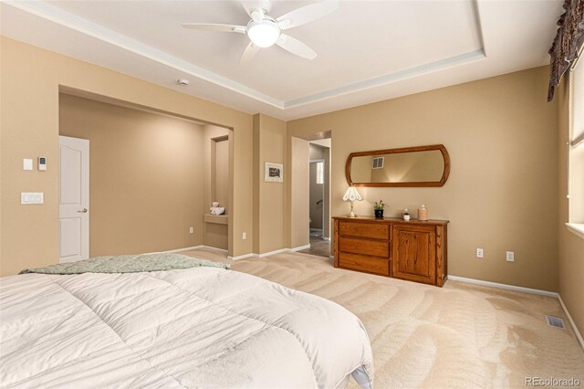 bedroom with a tray ceiling, light carpet, and ceiling fan