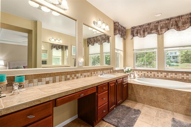 bathroom with decorative backsplash, tiled tub, vanity, and tile patterned floors