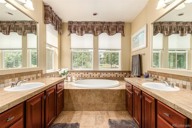 bathroom featuring tasteful backsplash, vanity, tile patterned floors, and a relaxing tiled tub