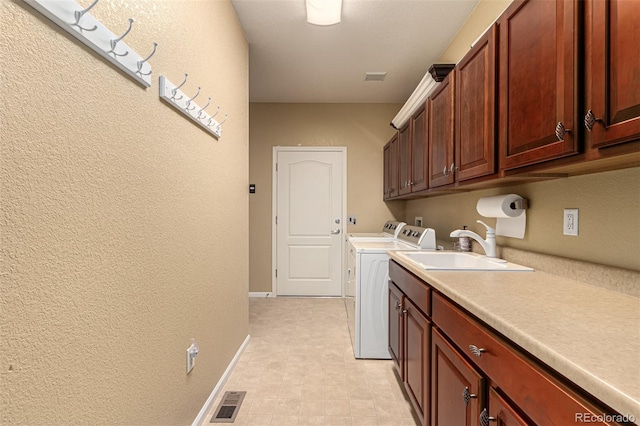 clothes washing area featuring cabinets, sink, and washer and dryer