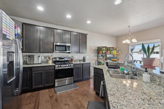 2431 Nicholson St, Berthoud, CO 80513 - kitchen featuring stainless steel appliances, a sink, a chandelier, a textured ceiling, and dark wood-style flooring