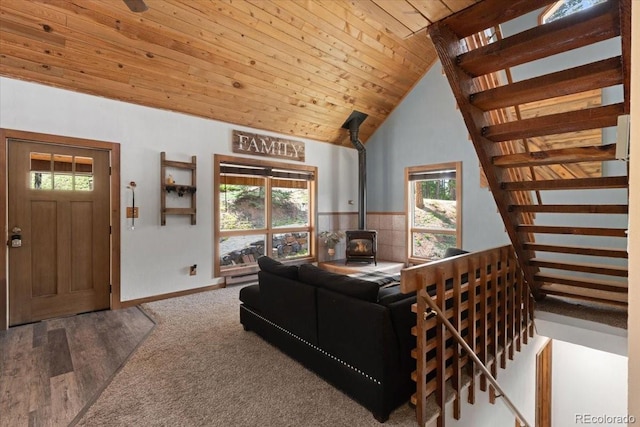 11724 Little Turtle Ln, Conifer, CO 80433 - living area featuring a wood stove, healthy amount of natural light, wood ceiling, stairway, and baseboards