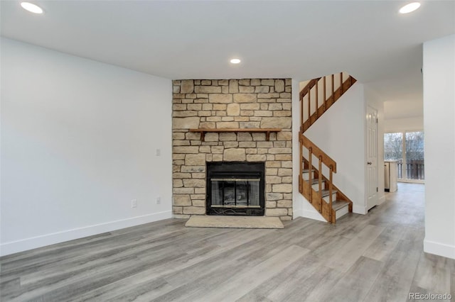 unfurnished living room with stairway, wood finished floors, baseboards, recessed lighting, and a fireplace