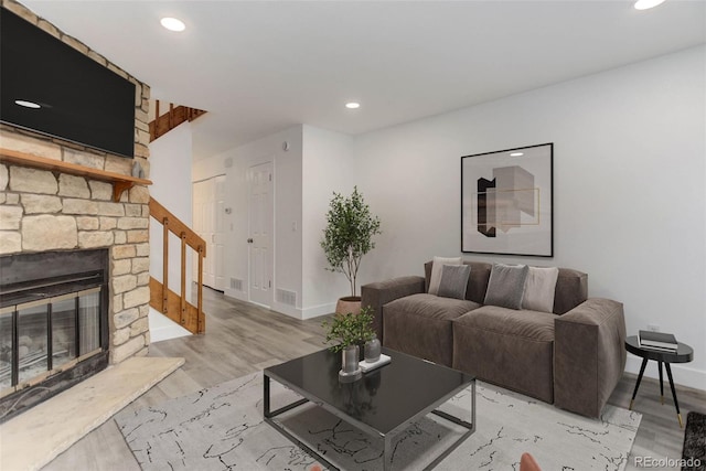 11973 E Kepner Dr, Aurora, CO 80012 - living room with baseboards, recessed lighting, light wood-style flooring, stairs, and a stone fireplace