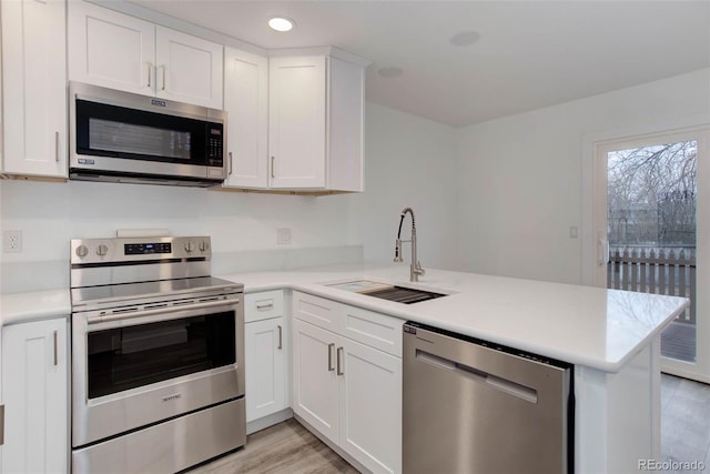 11973 E Kepner Dr, Aurora, CO 80012 - kitchen featuring appliances with stainless steel finishes, a sink, a peninsula, light countertops, and recessed lighting