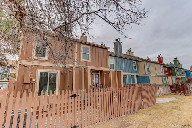 11973 E Kepner Dr, Aurora, CO 80012 - back of house featuring a chimney, a fenced front yard, and board and batten siding