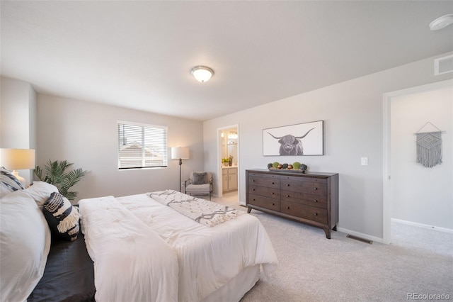 bedroom with light colored carpet and connected bathroom