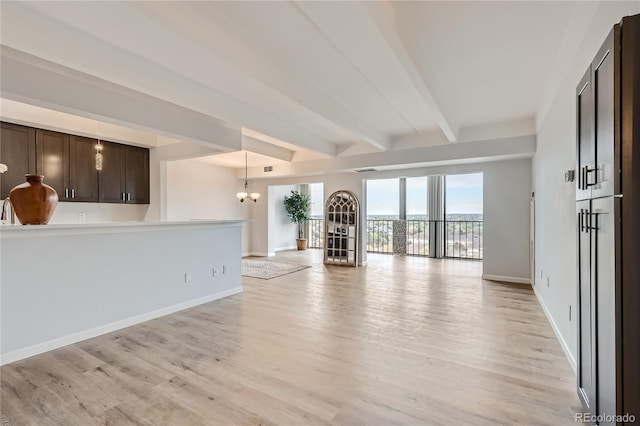 unfurnished living room with beam ceiling, light hardwood / wood-style flooring, and an inviting chandelier