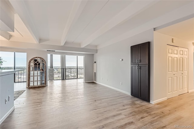 unfurnished living room featuring light hardwood / wood-style flooring, beamed ceiling, and a wealth of natural light