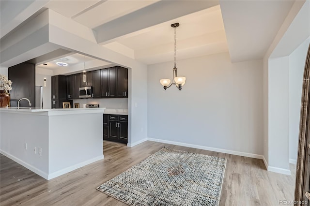 kitchen featuring appliances with stainless steel finishes, light hardwood / wood-style flooring, decorative light fixtures, and a notable chandelier