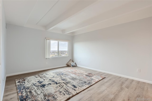 spare room with light hardwood / wood-style floors and beamed ceiling