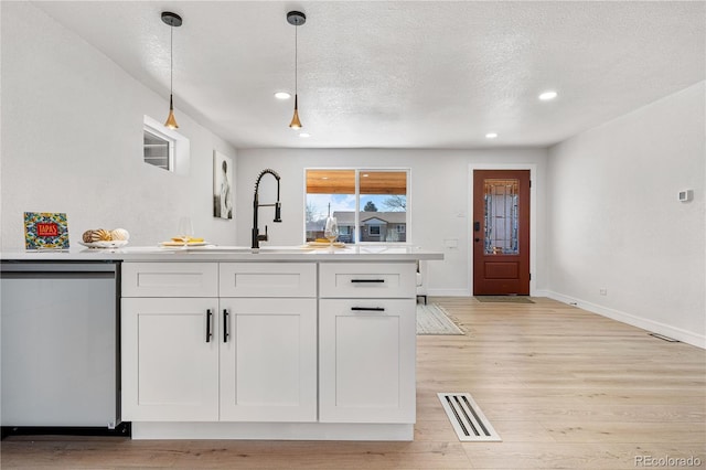 kitchen featuring white cabinetry, dishwasher, hanging light fixtures, a textured ceiling, and light hardwood / wood-style flooring