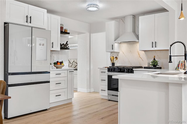 kitchen with stainless steel range with gas cooktop, sink, white cabinets, white refrigerator, and wall chimney range hood