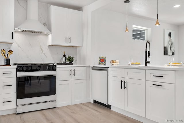 kitchen with range, light hardwood / wood-style flooring, hanging light fixtures, wall chimney range hood, and white cabinets