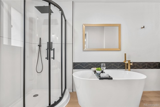 bathroom featuring tile walls, hardwood / wood-style floors, and plus walk in shower