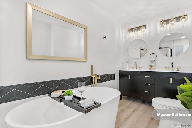 bathroom with hardwood / wood-style flooring, toilet, vanity, and a tub to relax in