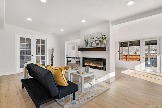 living room with vaulted ceiling, light wood-type flooring, and french doors