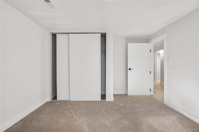 unfurnished bedroom featuring light carpet and a closet