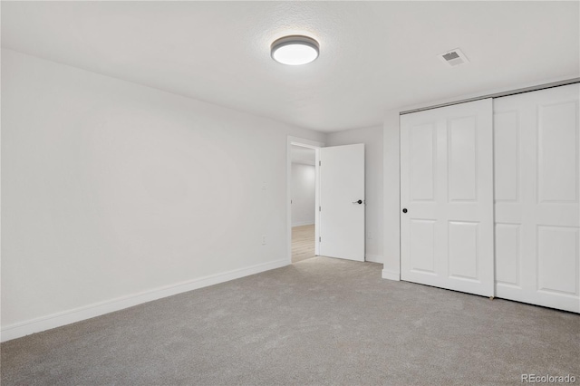 unfurnished bedroom featuring light colored carpet and a closet