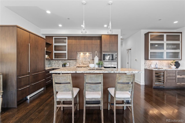 kitchen with dark hardwood / wood-style floors, decorative light fixtures, black microwave, oven, and beverage cooler