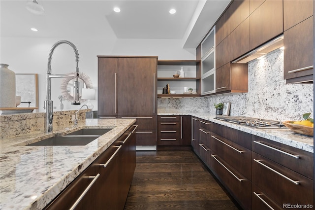 kitchen with sink, dark wood-type flooring, tasteful backsplash, light stone countertops, and stainless steel gas cooktop