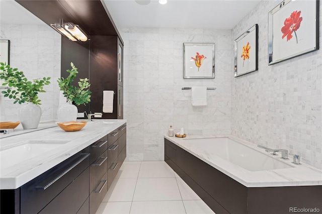 bathroom featuring tile patterned flooring, vanity, a tub, and tile walls