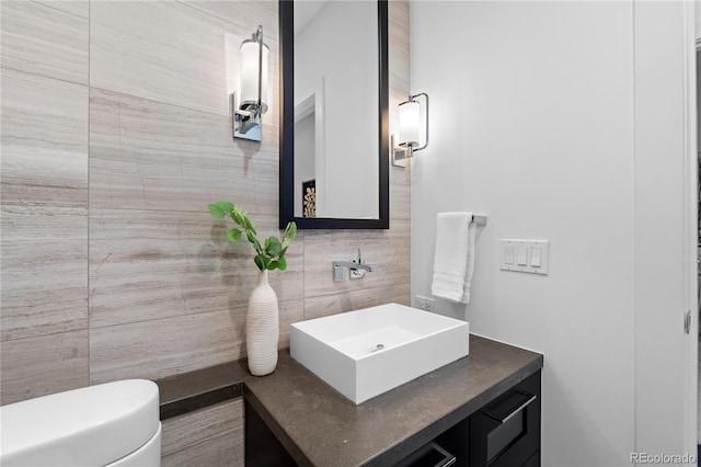 bathroom featuring vanity, tile walls, and toilet