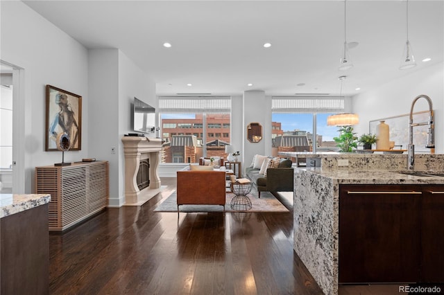 kitchen featuring hanging light fixtures, light stone countertops, sink, and dark hardwood / wood-style floors