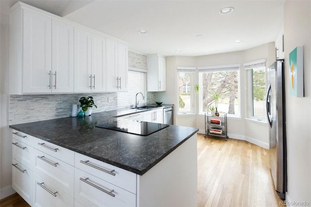 kitchen with a sink, decorative backsplash, stainless steel appliances, and light wood finished floors