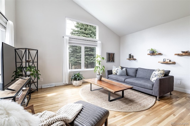 living room featuring visible vents, baseboards, wood finished floors, and high vaulted ceiling