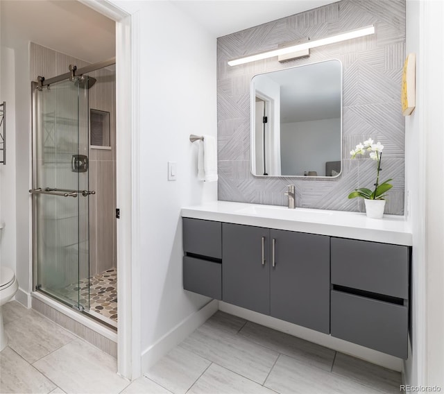 bathroom with vanity, toilet, baseboards, and a stall shower