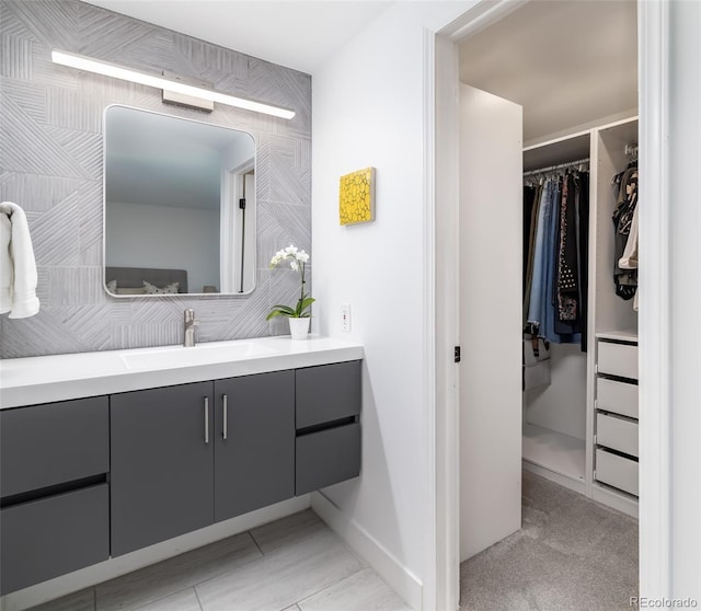 bathroom featuring baseboards, a spacious closet, and vanity