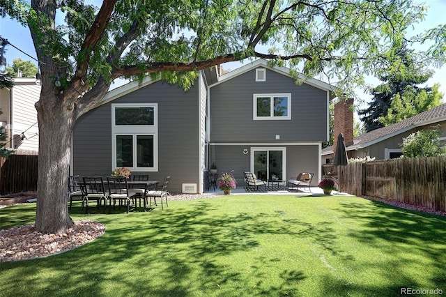 rear view of house with a yard, a fenced backyard, and a patio area