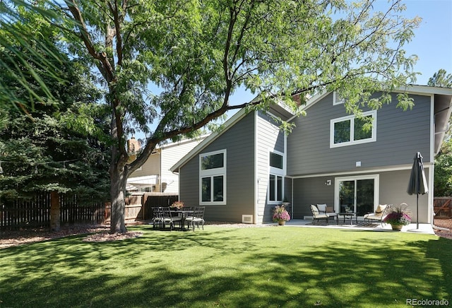 rear view of property featuring a lawn, a patio area, and fence