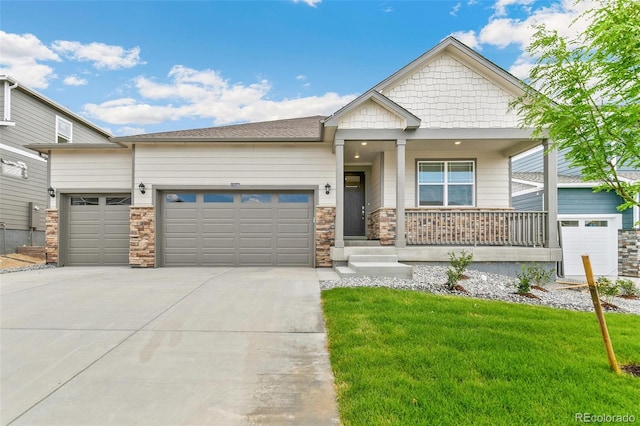 craftsman inspired home with concrete driveway, an attached garage, covered porch, and a front lawn