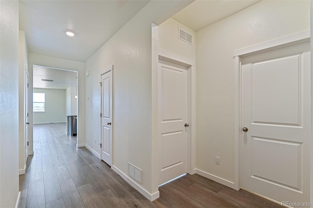 corridor featuring visible vents, baseboards, and dark wood-type flooring