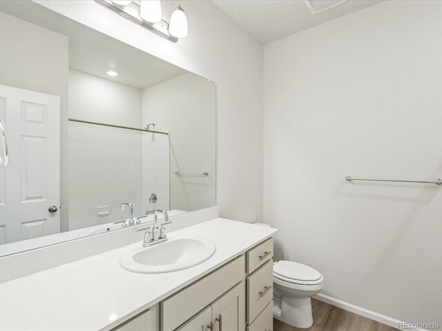 bathroom featuring vanity, toilet, hardwood / wood-style floors, and a shower