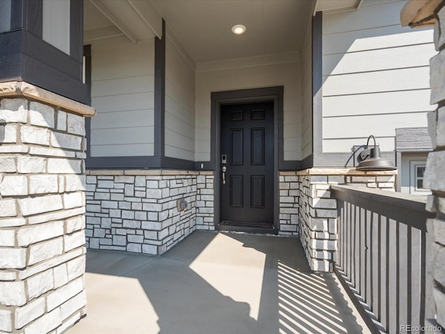 property entrance with a porch and stone siding