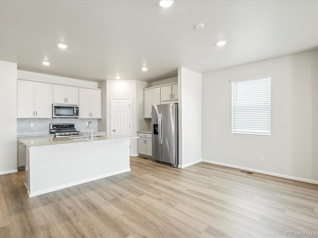 kitchen with tasteful backsplash, light countertops, appliances with stainless steel finishes, light wood-type flooring, and baseboards