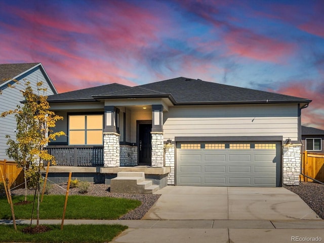 view of front of house with a porch, a garage, fence, concrete driveway, and stone siding