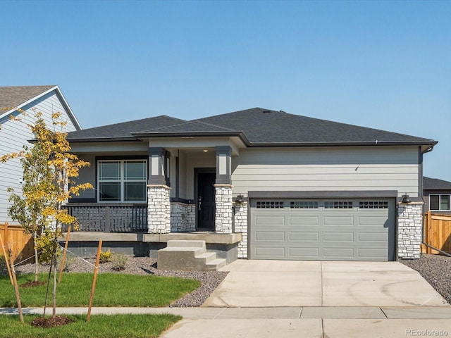 prairie-style home with driveway, stone siding, a garage, and fence