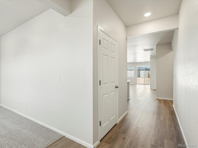 hall featuring wood finished floors, visible vents, and baseboards